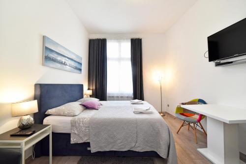 萨格勒布Deluxe Apartments Ria的一间卧室配有一张床、一张书桌和一台电视。