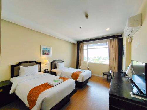 彭世洛Wangchan Riverview的酒店客房设有两张床和一台平面电视。