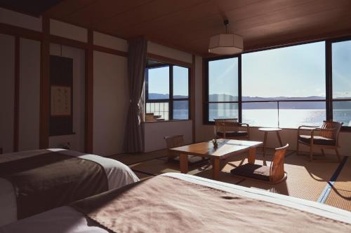 诹访市宿诹访湖日式旅馆的客房设有床、桌子和一些窗户。
