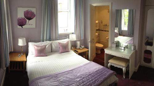 邓弗里斯劳伦之家旅馆的卧室配有一张带粉红色枕头的大床