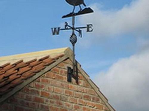 柯比穆尔赛德砖厂农舍住宿加早餐旅馆的鸟儿在建筑物顶上,有风帆