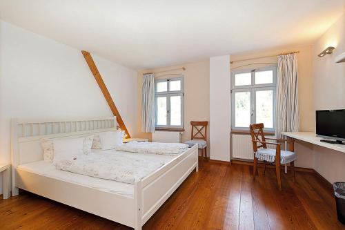 KrippenLandgasthaus Ziegelscheune的一间卧室配有白色的床、一张书桌和两个窗户。