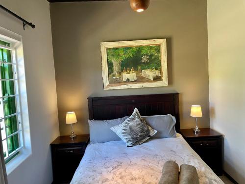 赫曼努斯Kleine Vrede Farm Cottage的一间卧室配有一张带两盏灯和一幅画的床铺
