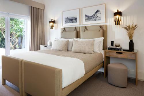 开普敦Kaap Mooi Luxury Guest House的一间卧室配有一张大床、一张桌子和一个窗户。