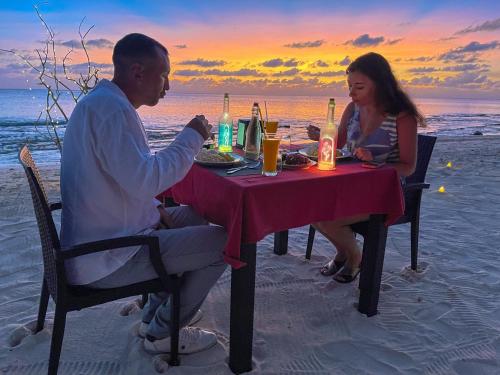 图杜Thoddoo Sunny Beach的坐在海滩桌子上的男人和女人