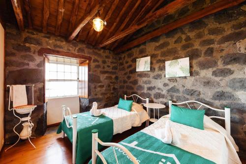 Santo Amaroholiday home, Santo Amaro, Pico, Azores的一间带两张床铺的卧室,位于带石墙的房间内