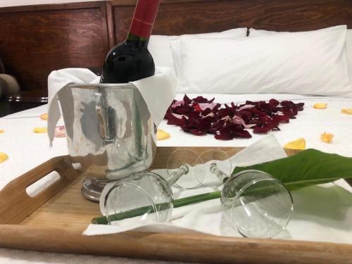 圣胡安特奥蒂瓦坎Hotel CALLI YOLOTL Teotihuacan的床上的托盘,上面装有玻璃杯和一瓶葡萄酒