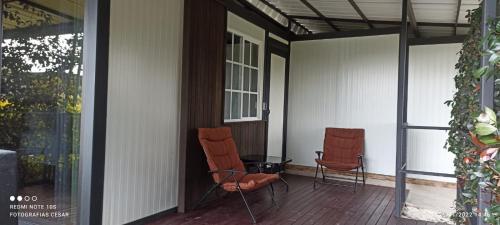 里奥内格罗Hotel & Golf Isak Aeropuerto的两把椅子坐在房子的门廊上