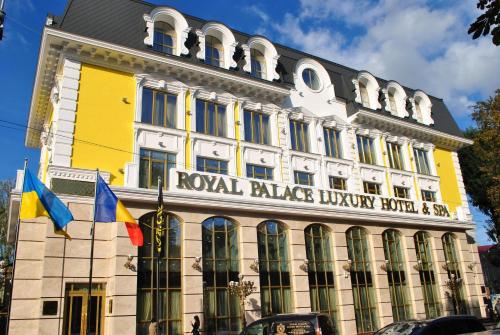 赫梅利尼茨基Royal Palace Luxury Hotel and SPA的前面有旗帜的黄色和白色建筑