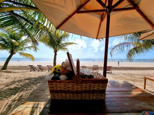 马拉戈日Pousada Enero的海滩上的遮阳伞下的野餐篮