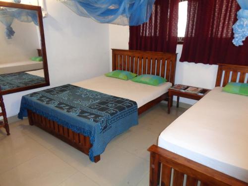 韦勒沃耶Saranga Holiday Inn的一间卧室配有两张床和镜子