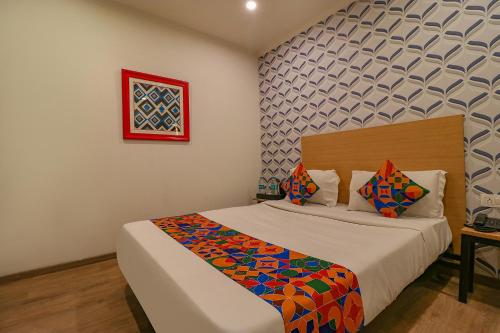 新德里FabHotel Chattarpur Enclave的一间卧室配有一张带彩色毯子的床