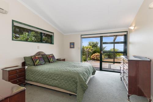 OpuaBreezy on Broadview - Opua Holiday Home的一间卧室设有一张床和一个滑动玻璃门