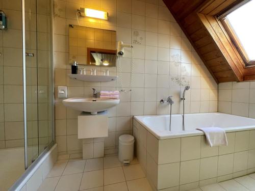 Eresing韦德曼乡村酒店的一间带水槽、浴缸和淋浴的浴室