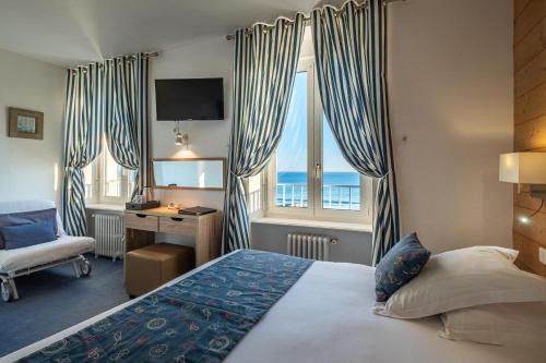 欧迪耶讷海滩酒店餐厅的酒店客房设有一张床、一张书桌和窗户。