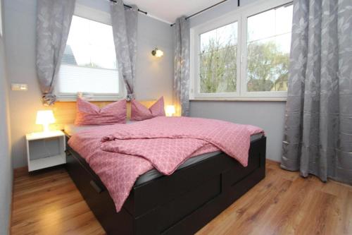 马尔肖Apartment, Malchow的一间卧室配有一张带粉色毯子的床和两个窗户