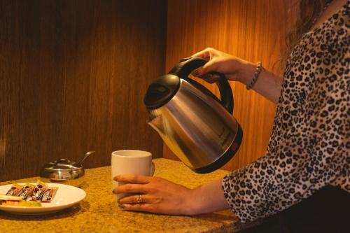 苏克雷San Juan Suites的把茶壶放在桌子上的女人,拿着杯
