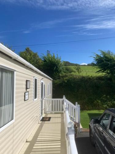 纽基Mollys Retreat pet friendly three bed caravan with small garden Newquay Bay Resort Quieter area of park的一座带门廊的房子,旁边停着一辆汽车