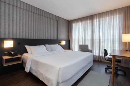 伊达贾伊Hilton Garden Inn Praia Brava的卧室配有一张白色大床和一张书桌