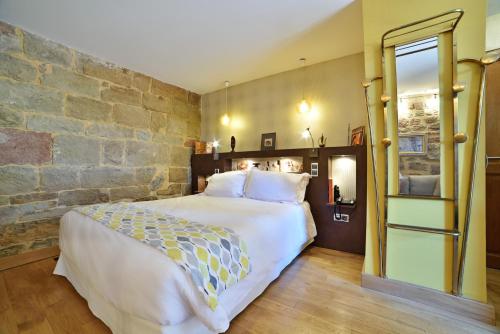 Noailhac巴斯提迪旅馆的一间卧室设有一张大床和石墙