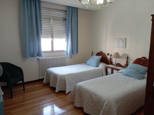 坎巴多斯Casa Pepa的一间卧室设有两张床,窗户配有蓝色窗帘