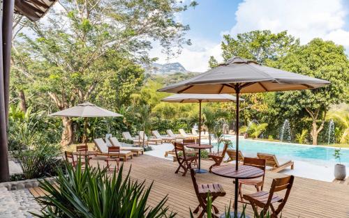杰里科Casa Jacaranda Hotel Boutique的一个带桌椅的户外庭院和一个游泳池