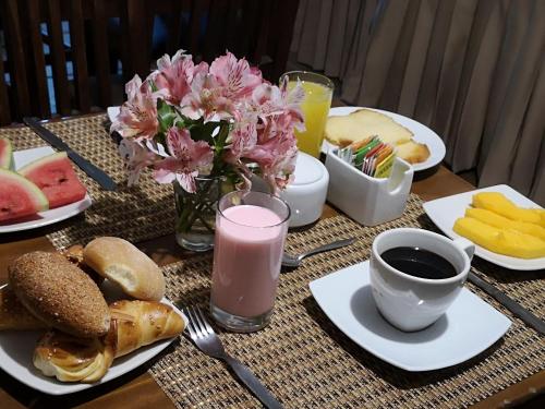 马丘比丘Hotel Tara Machupicchu的餐桌上放着食物盘子和粉色饮料