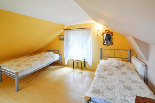 什切齐内克holiday home, Spore的配有两张床的客房,设有黄色的墙壁和窗户