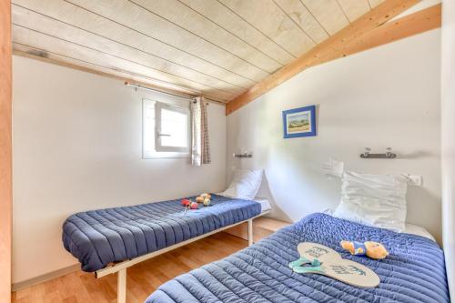 河镇Camping maeva Escapades Le Domaine du Cèdre的一间卧室设有两张床和窗户。