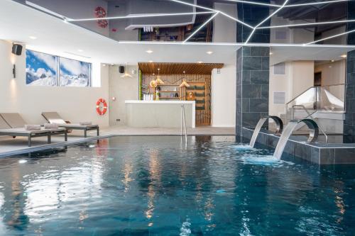 蒂涅Hôtel VoulezVous by Les Etincelles的一座带水滑梯的室内游泳池