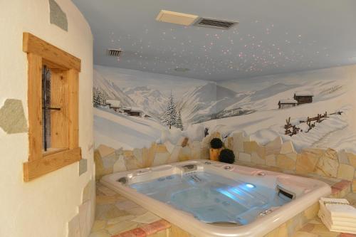 利维尼奥Hotel Crosal的一个带按摩浴缸的房间,上面画着一幅雪山的画作