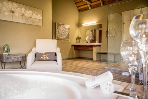 提姆巴瓦提禁猎区康巴库河畔山林小屋的带浴缸、椅子和眼镜的浴室
