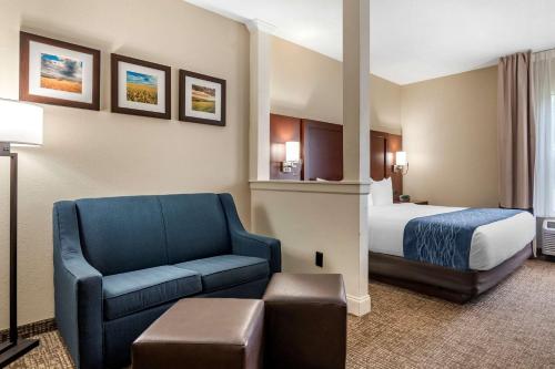 章克申城Comfort Inn & Suites Junction City - near Fort Riley的酒店客房,配有一张床和一张蓝色椅子
