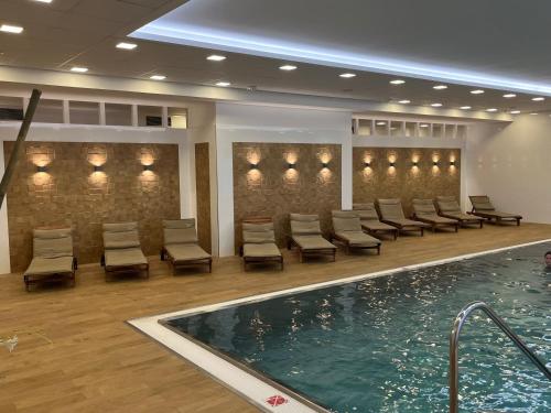 卡罗维发利Moser Wellness Apartments的酒店大堂的游泳池,设有椅子和游泳池