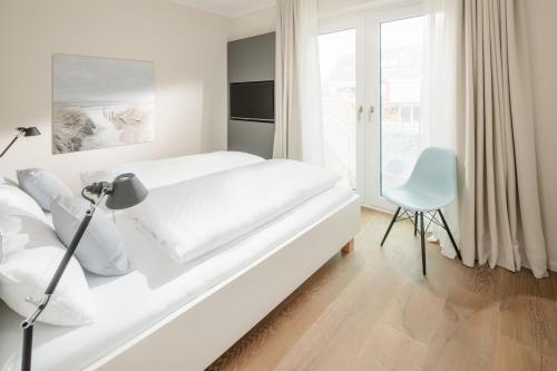 于斯德meer suite juist 5 - mit Wattblick的白色卧室配有白色的床和椅子