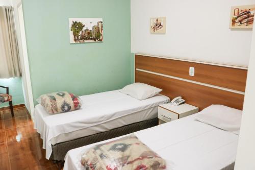 圣若泽杜斯坎普斯Hotel Jardim Sul的一间设有两张床的房间,内配电话