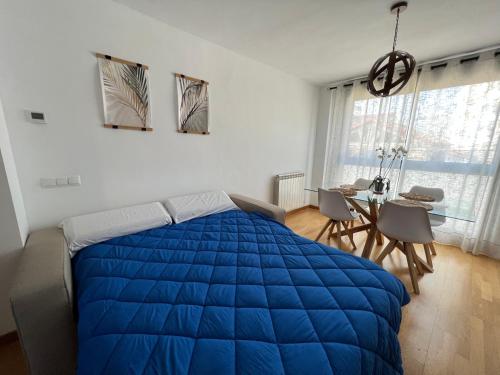 萨拉戈萨El Llano Zaragoza的一间卧室配有一张蓝色的大床和一张桌子