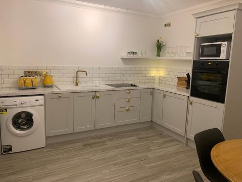韦斯特波特Alta House的厨房配有白色橱柜、洗衣机和烘干机