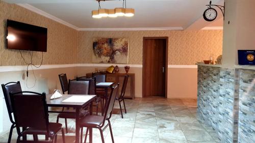 卡兹贝吉Nikolo Inn的餐厅设有桌椅和墙上的时钟
