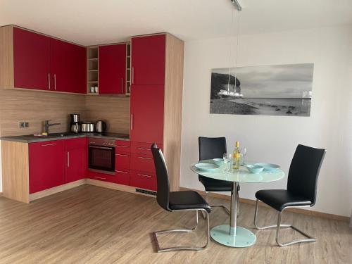 巴贝Traumferienwohnung Ostseebad Baabe - Rügen的厨房配有红色橱柜和桌椅