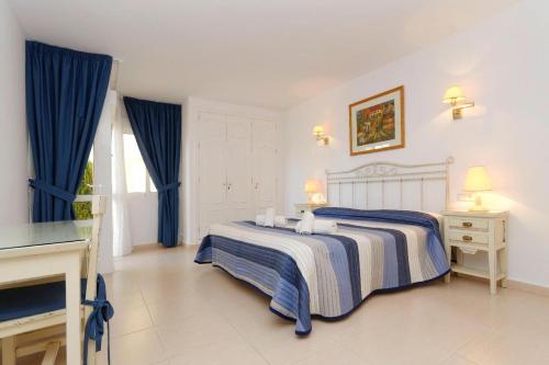 阿塔玛丽亚La Manga Club Resort - Los Olivos 54的一间卧室配有一张带蓝色窗帘的床和电视。