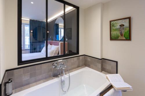 布里夫拉盖亚尔德Hôtel De Charme Le Chêne Vert的一间带浴缸和镜子的浴室