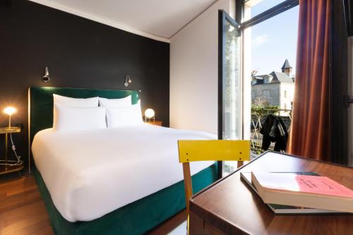 布里夫拉盖亚尔德Hôtel De Charme Le Chêne Vert的一间卧室配有一张床、一张书桌和一个窗户。