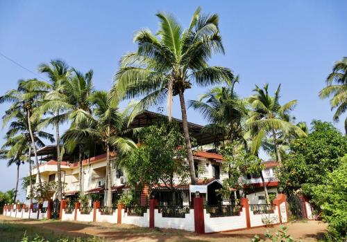 坎多林SHANU'S SEASIDE INN - A Guesthouse, 100 metres to Candolim Beach的前面有棕榈树的酒店