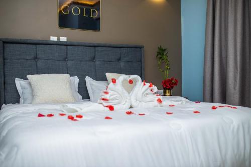 PeduasiPiano & Gold Collections, Peduase的一张白色的床,上面有红玫瑰
