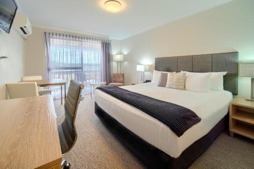 奥尔巴尼Albany Motel & Apartments的酒店客房设有一张大床和一张书桌。