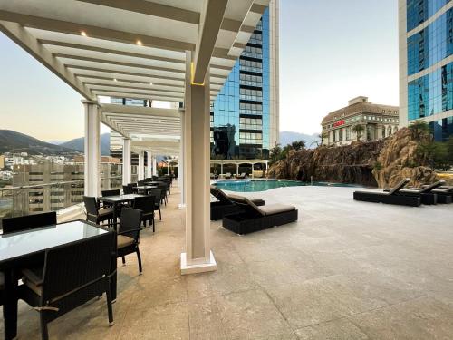 蒙特雷Safi Royal Luxury Metropolitan的一座带桌椅的庭院和一座位于大楼内的游泳池