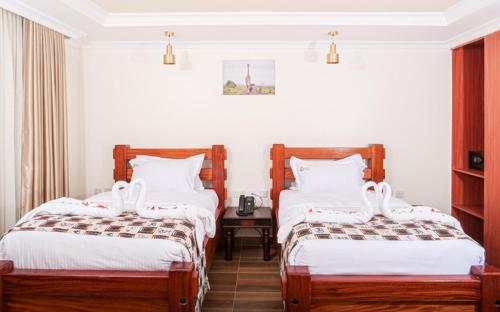 内罗毕Pori City Hotel的酒店客房设有两张床和一张桌子。
