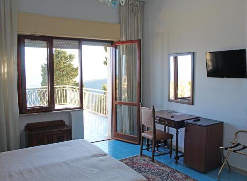 陶尔米纳米迪泰拉尼酒店的一间带一张床和一张书桌的卧室以及一个阳台