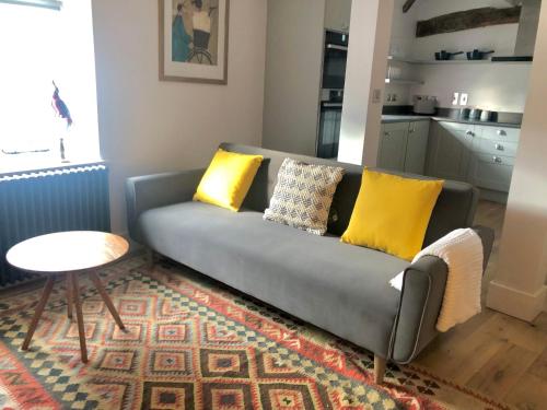 斯坦福德3 The Olde Barn Apartments的客厅里配有带黄色枕头的灰色沙发
